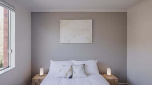 A bedroom with a bed, two bedside tables with lamps, a window, and a wall-mounted artwork. - Valley View 6 | Lenah Valley (Hobart City)