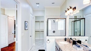 Un baño moderno con dos lavamanos, un espejo grande y cabina de ducha.