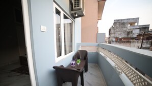 Ein Balkon mit Tisch, Stühlen, einer Topfpflanze und einem Fenster.