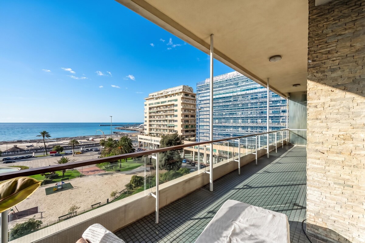 A balcony with a view of the beach and a building.
