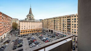 A multi-story parking garage with a view of a tall building with a spire in the background. - Piazza Rossetti Apartments (Genoa)
