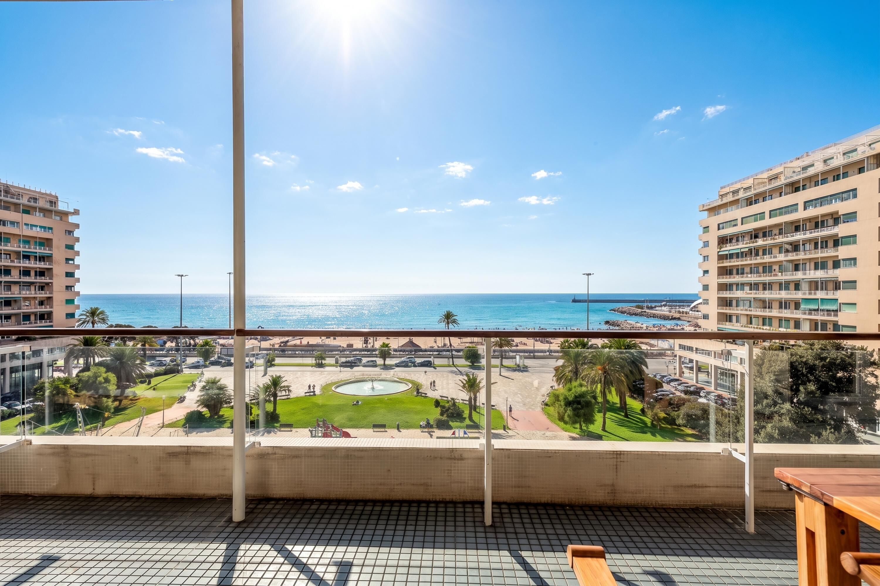 A balcony with a view of a beach and a parking lot.
