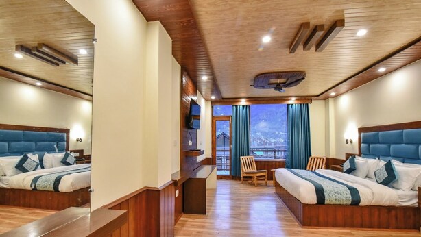 A hotel room with two beds, wooden flooring, a balcony with a view, and a wooden ceiling. - Sky Bird Nest (Manali)