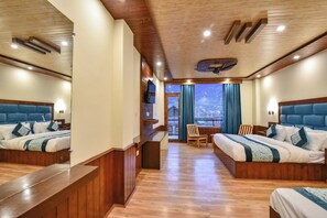Habitación de hotel con dos camas, suelo de madera, balcón con vistas y techo de madera.