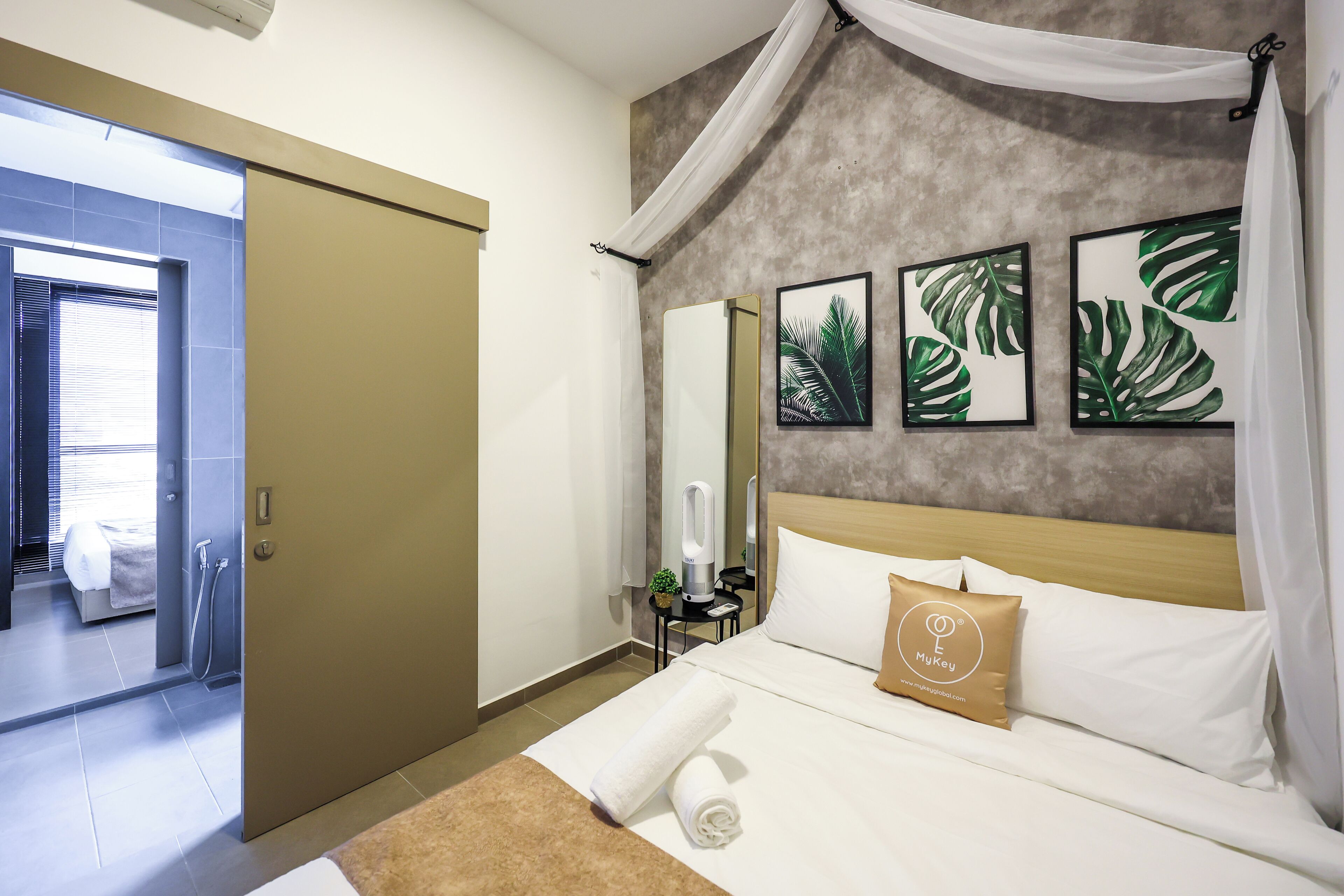 A hotel room with a bed, a nightstand, a mirror, and artwork on the wall.
