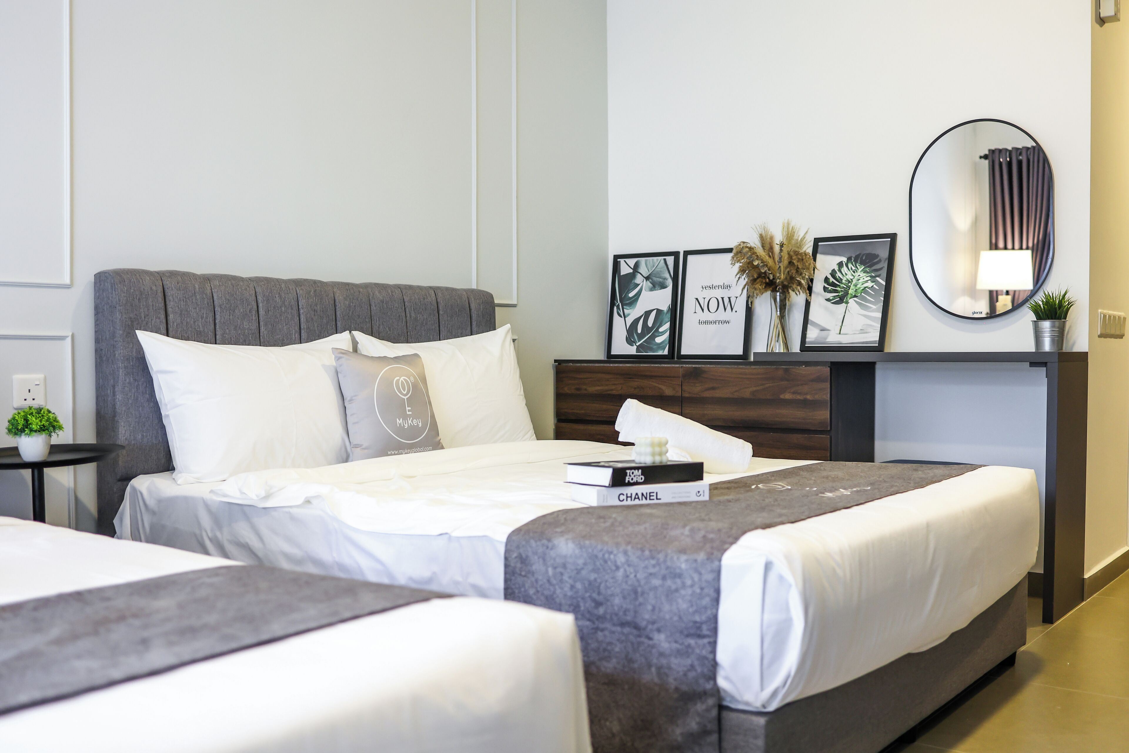 Una habitación de hotel moderna con una cama grande, una mesita de noche con lámpara y cuadros en la pared.