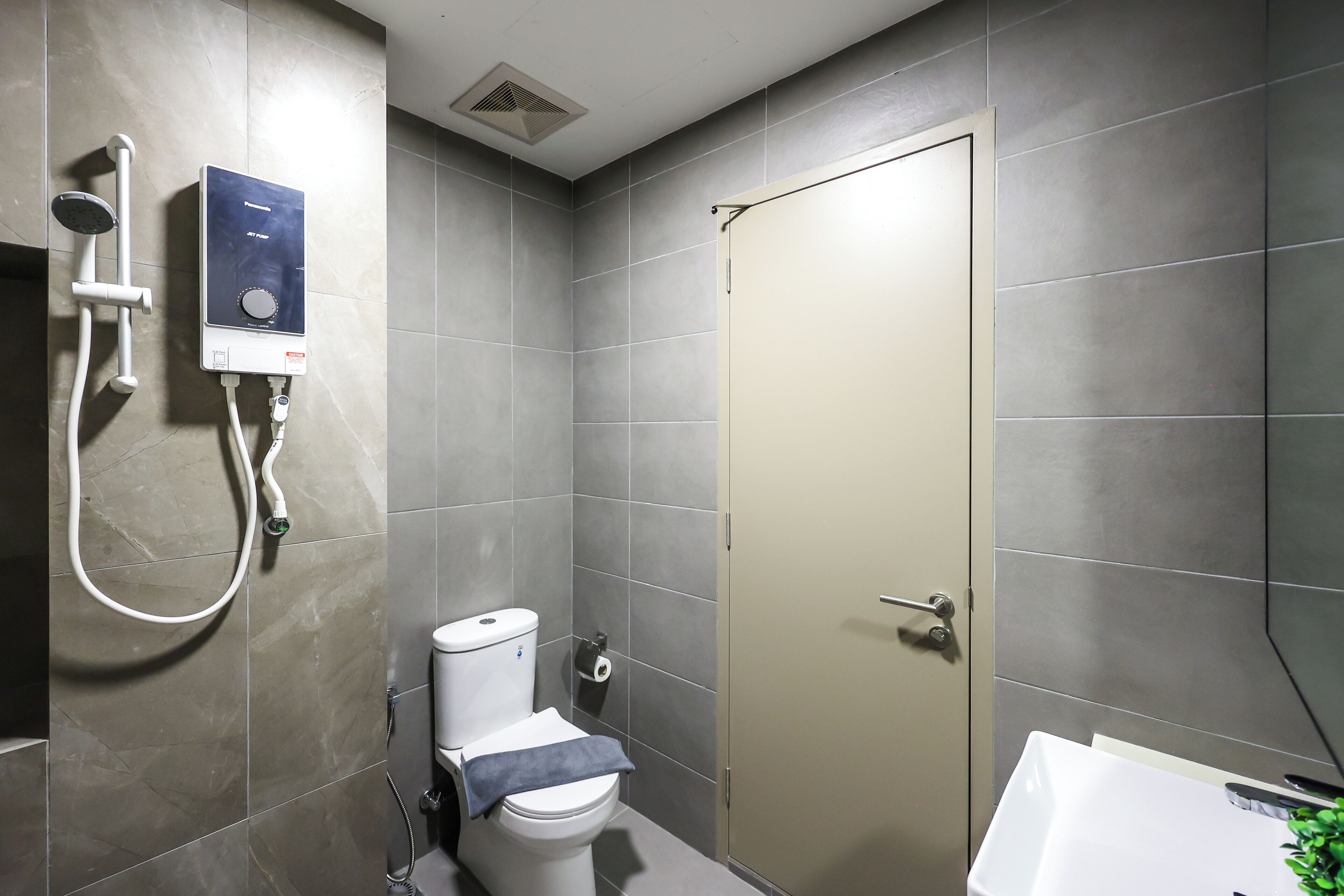 Een moderne badkamer met toilet, douche en wastafel.