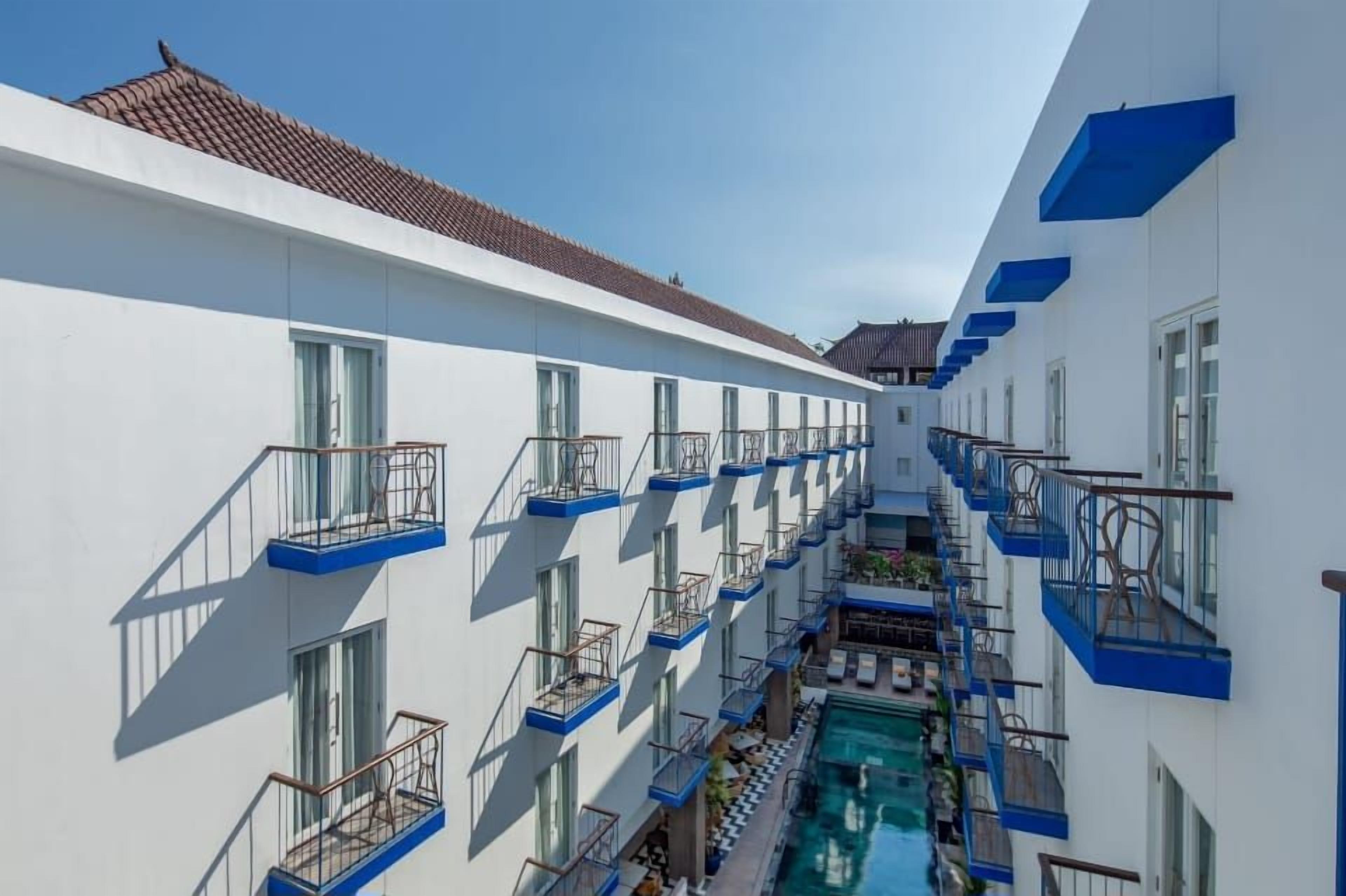 Un hôtel à plusieurs étages, doté de balcons et d’une piscine.