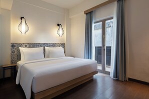 A hotel room with a large bed, two wall-mounted lamps, a patterned headboard, and a view through a sliding door. - Kampi Hotel Legian (Legian)