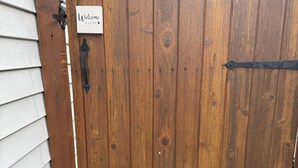Une porte en bois avec une pancarte indiquant «Bienvenue chez nous», un loquet en métal et une marche en béton menant à la porte.