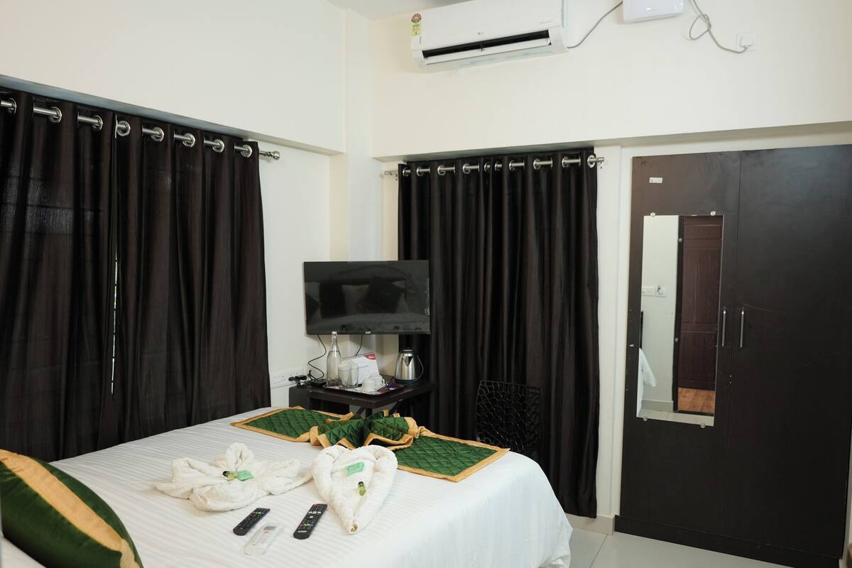 Una camera d'albergo con un letto, una TV, un armadio e un condizionatore d'aria.