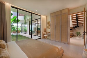 A modern bedroom with a large bed, sliding glass doors leading to a patio, and a staircase. - Sona Villa by Betterplace (Canggu)
