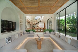A modern interior with a central seating area, a staircase, and large windows. - Sona Villa by Betterplace (Canggu)