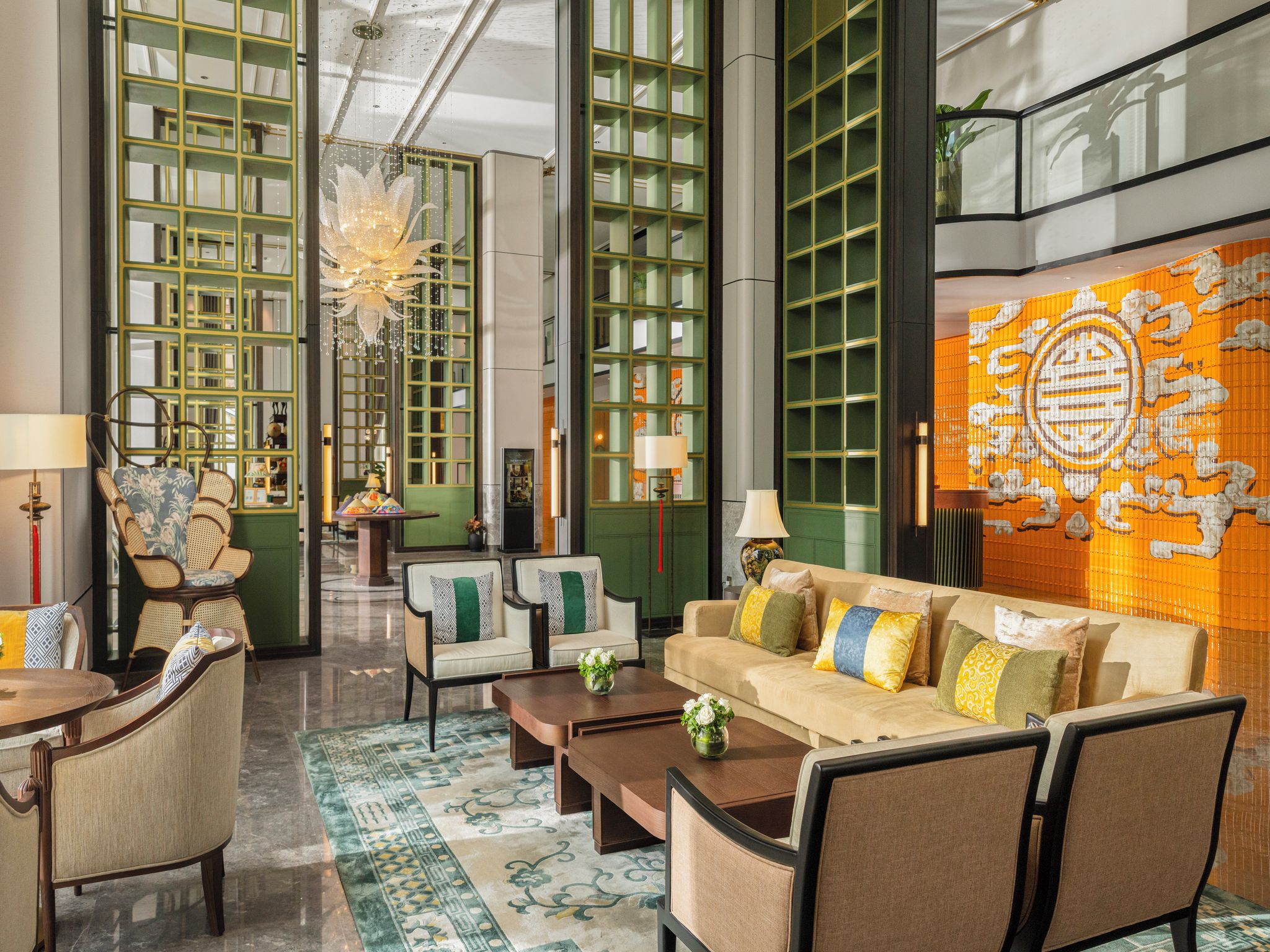 A spacious lobby with a central seating area, a chandelier, and a large wall mural.