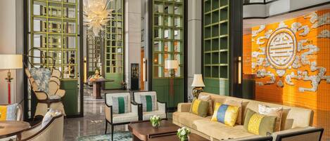 A spacious lobby with a central seating area, a chandelier, and a large wall mural.