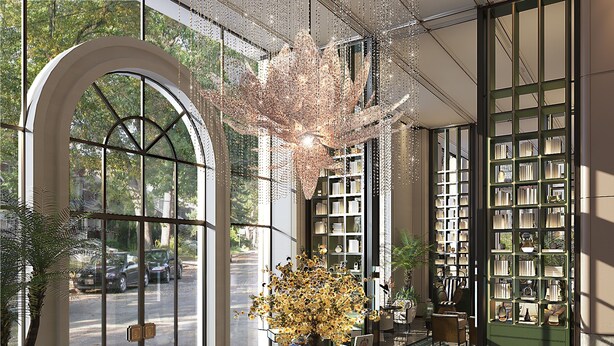 A spacious lobby with a large arched doorway, a central table with a vase of flowers, and a bookshelf filled with books. - Grand Royal Riverside Hue, Fusion Collection (Hue)