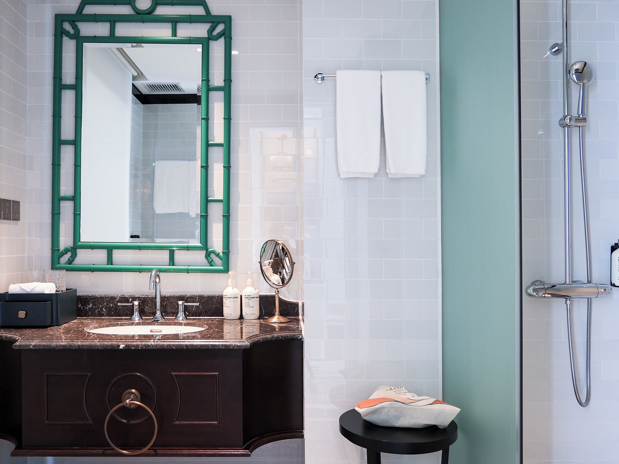 A bathroom with a marble sink, a mirror, a towel rack, and a shower.