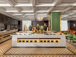 Un vestíbulo de hotel con zona de buffet, una araña y un piso con diseño.