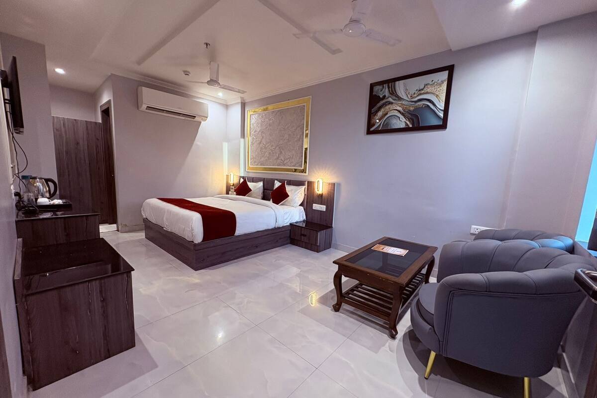 A modern hotel room with a bed, bedside tables, a desk, a chair, and a ceiling fan.