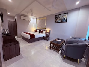Une chambre d’hôtel moderne équipée d’un lit, de tables de chevet, d’un bureau, d’une chaise et d’un ventilateur de plafond.