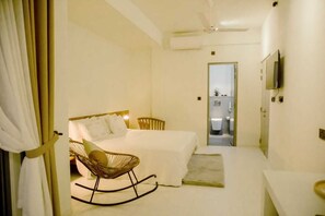 A bedroom with a bed, a rocking chair, a desk, and a bathroom visible through an open door. - Elysium Villa (Unawatuna)