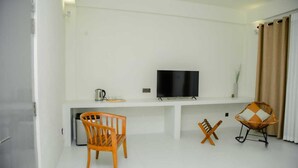 Una sala moderna con un televisor de pantalla plana, dos sillas de madera, una mesa de centro y un sofá.