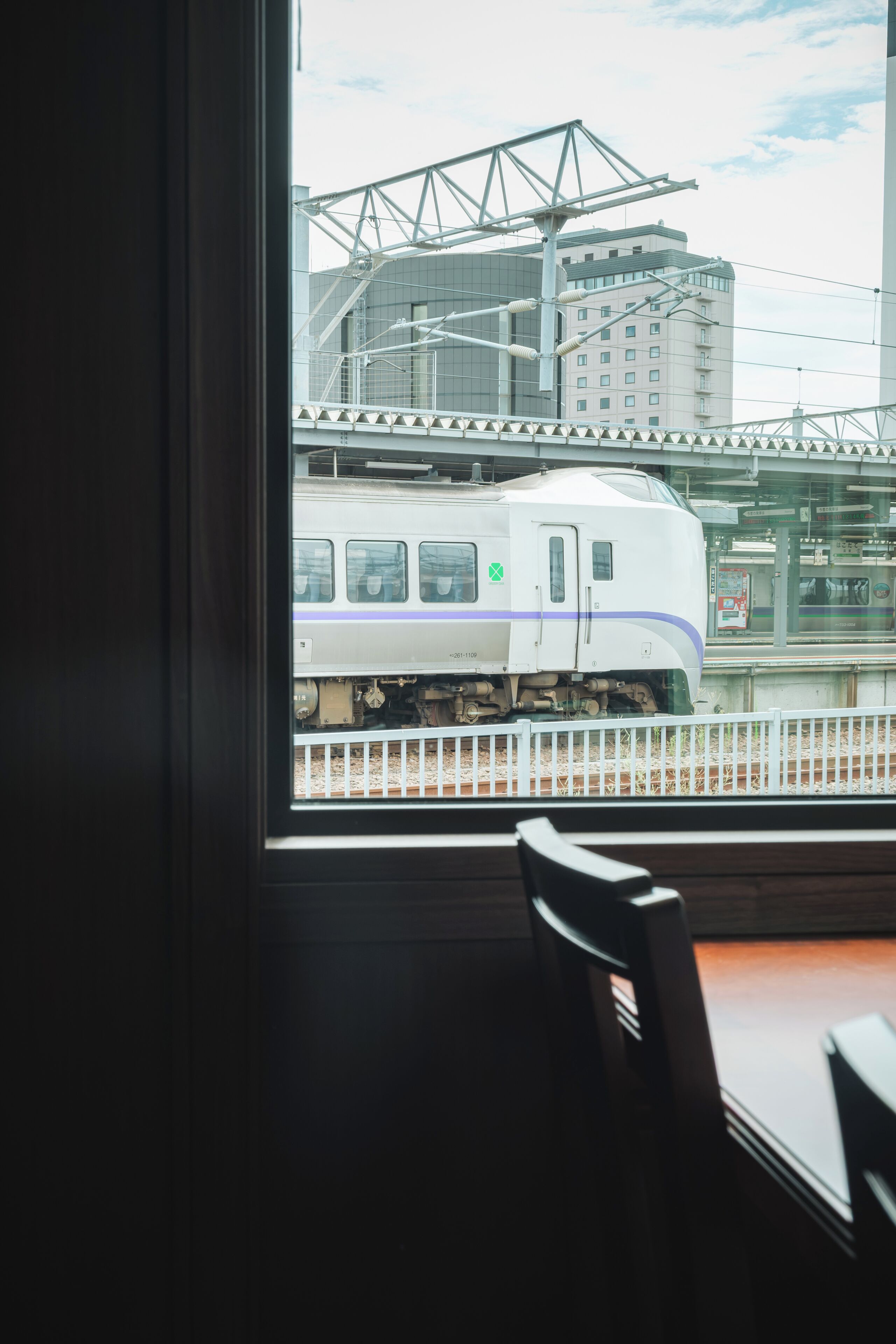A train station view through a window with a chair inside.