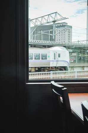 Udsigt til et togstation fra et vindue, med en stol indeni.