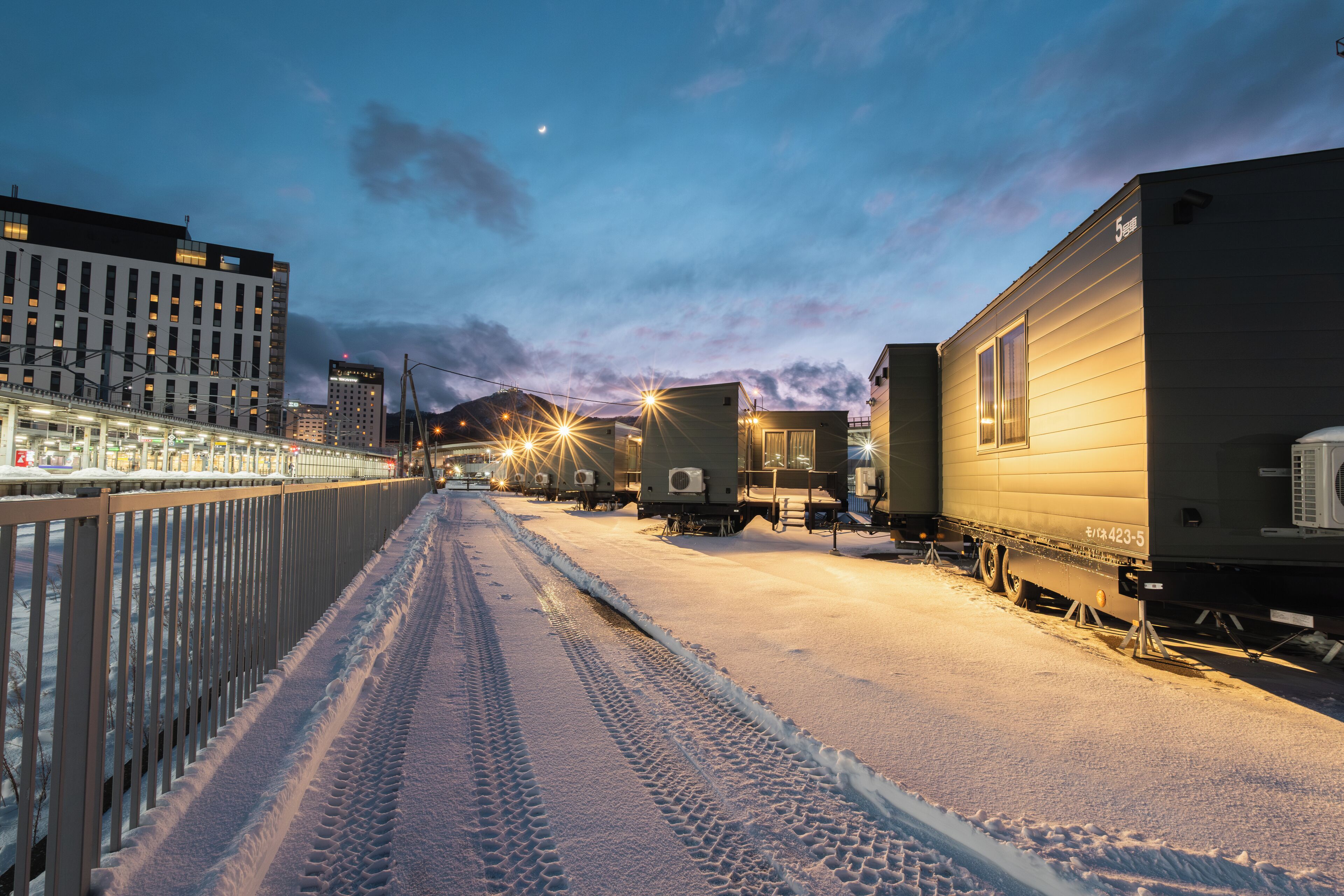 A snow-covered street with train cars parked on the right.