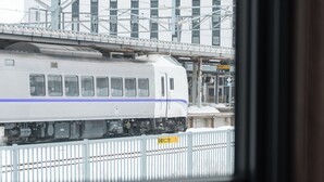 Une vue d’un train passant devant un bâtiment surmonté d’une structure métallique.