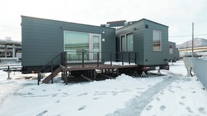 Un immeuble résidentiel moderne à deux étages, doté d’une terrasse et de grandes fenêtres.