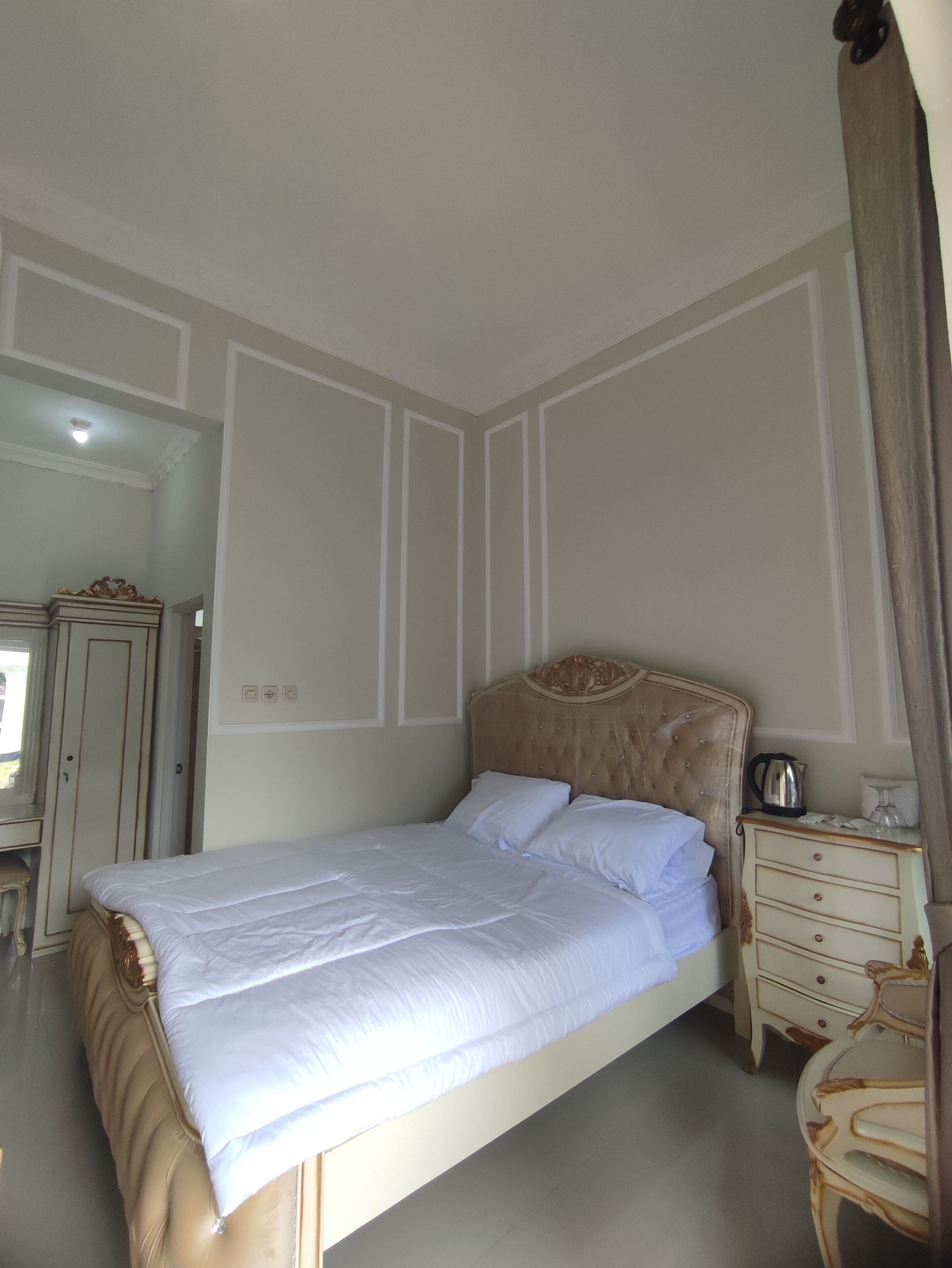 A bedroom with a large bed, a dresser, and a chair.