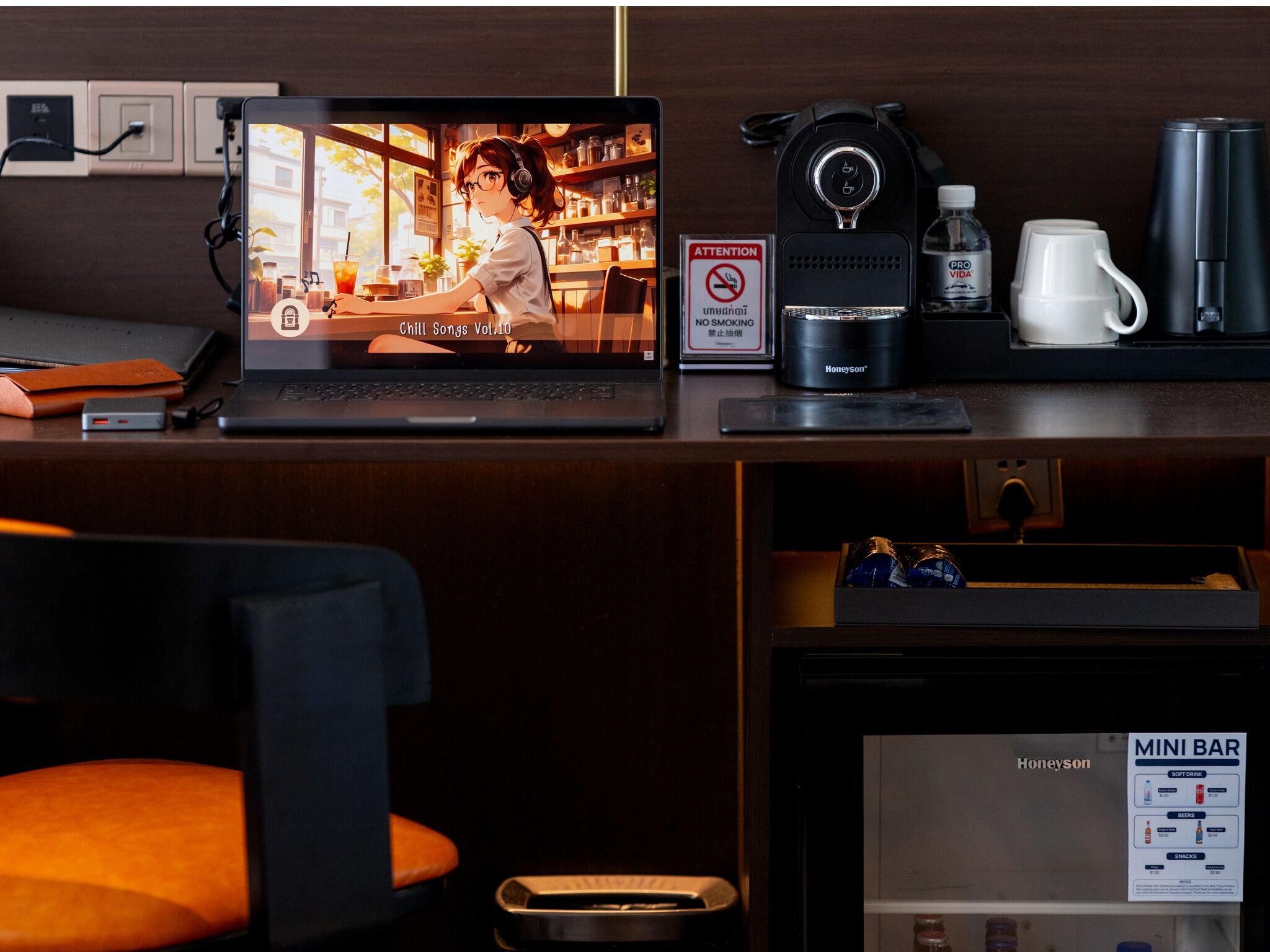 Een laptop met een video, een koffieapparaat, een minibars kastje en een rookvrij bord op een aanrecht.