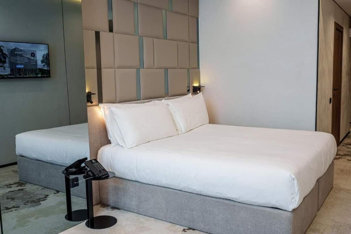 A hotel room with a large bed, a bedside telephone, and a wall-mounted light fixture.