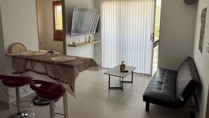 En moderne stue med spiseplads, en sort lædersofa og et lille bord.