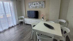 Un soggiorno moderno con zona pranzo, televisione a schermo piatto e ventilatore a soffitto.