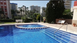 Una piscina con bordo piastrellato, una scala in metallo e una panchina.