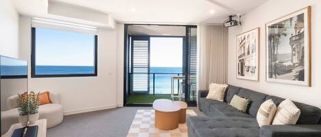 Ein modernes Wohnzimmer mit großem Fenster, einem grauen Sofa, einem Couchtisch und einem Flachbildfernseher.