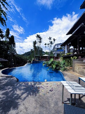 A swimming pool with a curved edge, surrounded by tropical plants and palm trees. - Serene Palm Heritage Tropical Villa (Taman Melawati)