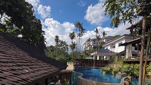 Ein Poolbereich mit einer Steintreppe, die zu einem Pool führt, umgeben von Palmen und einer überdachten Sitzgelegenheit.