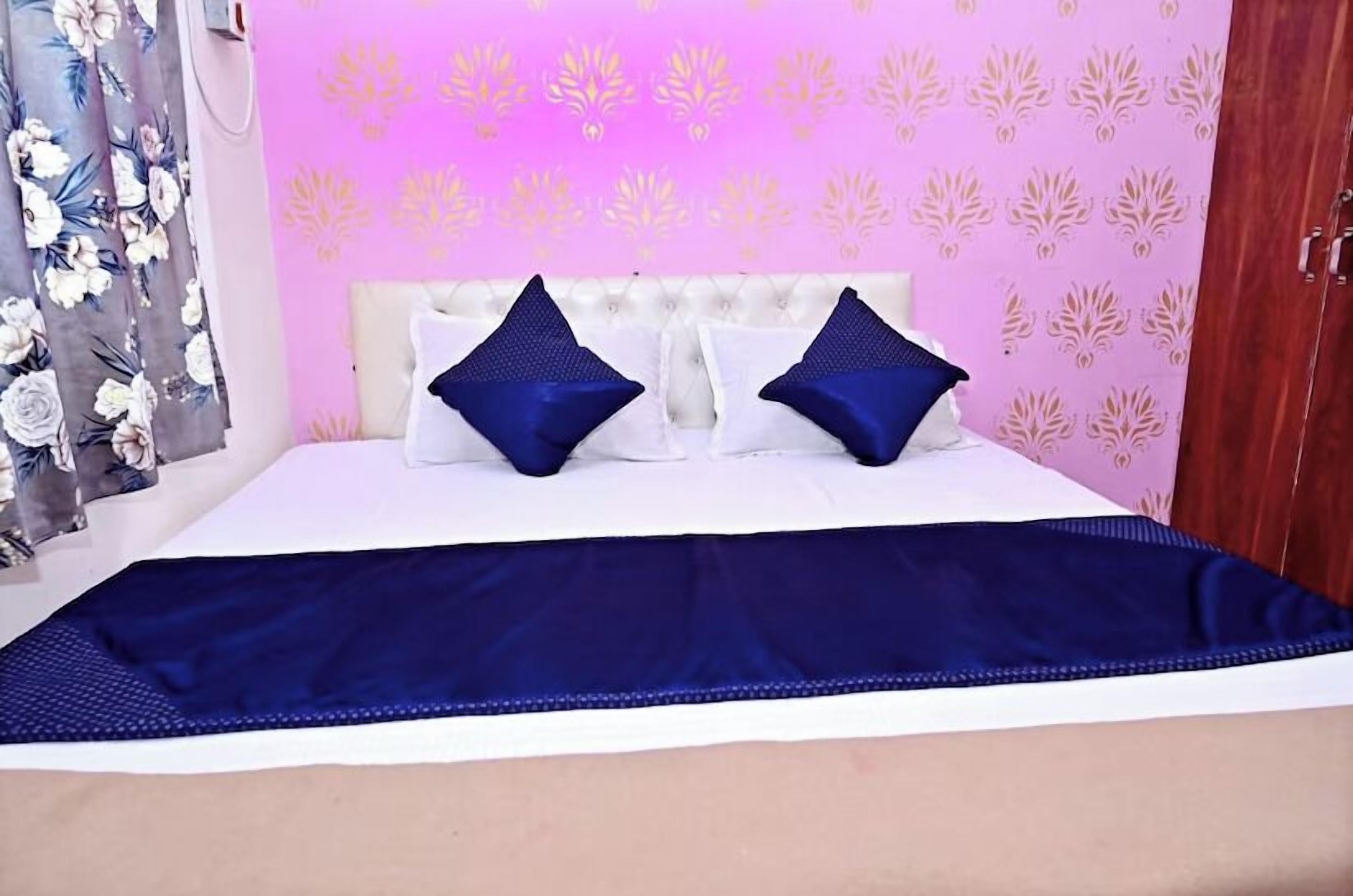 Een bed met een wit hoofdbord, twee blauwe kussens en een blauwe spreideken.