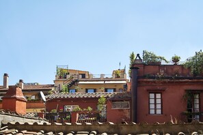 Un edificio residencial con fachada roja, antena parabólica visible y un pequeño balcón con plantas.