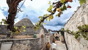 A narrow stone pathway flanked by rustic buildings with stone walls and tiled roofs. - Trulli Experience - Trulletto (Antonelli)