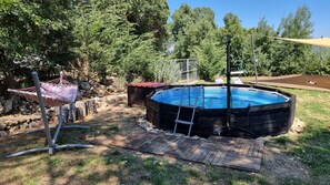 Un jardin avec un bain à remous en bois, un hamac et une terrasse en bois.