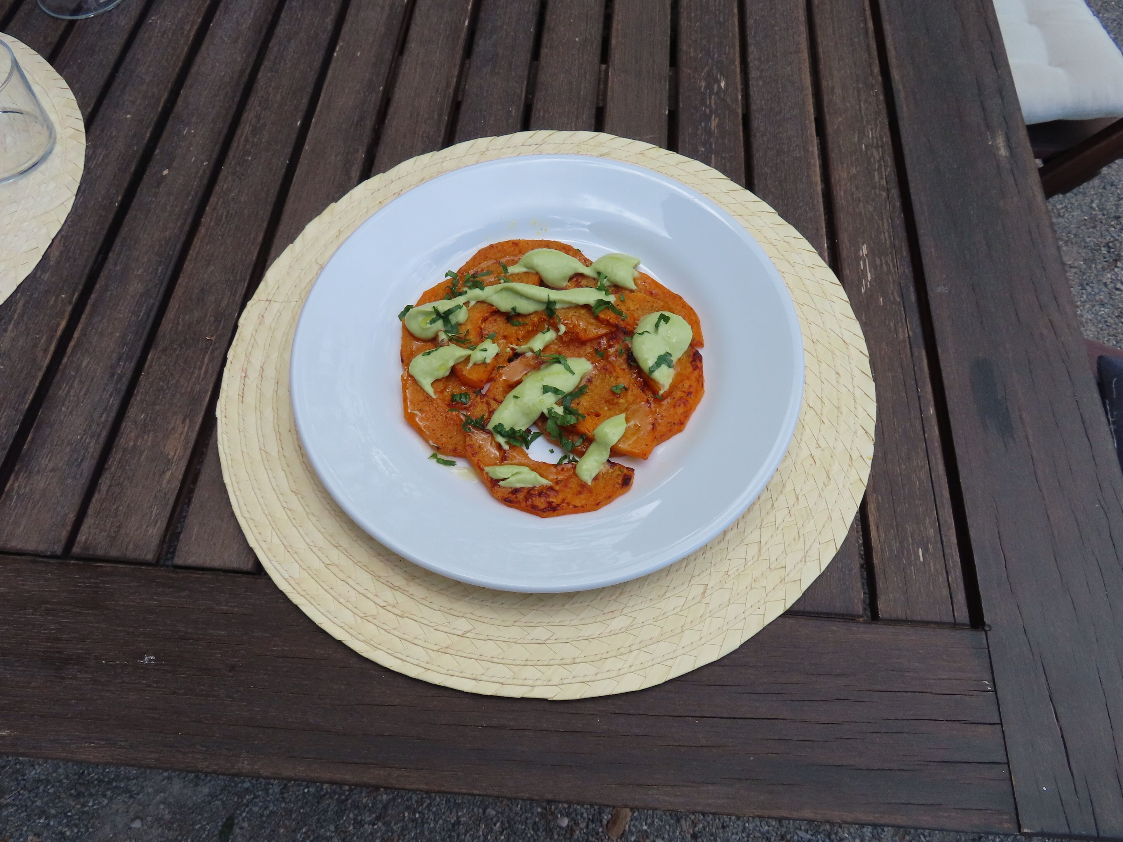 A white plate with a dish on a wooden table.