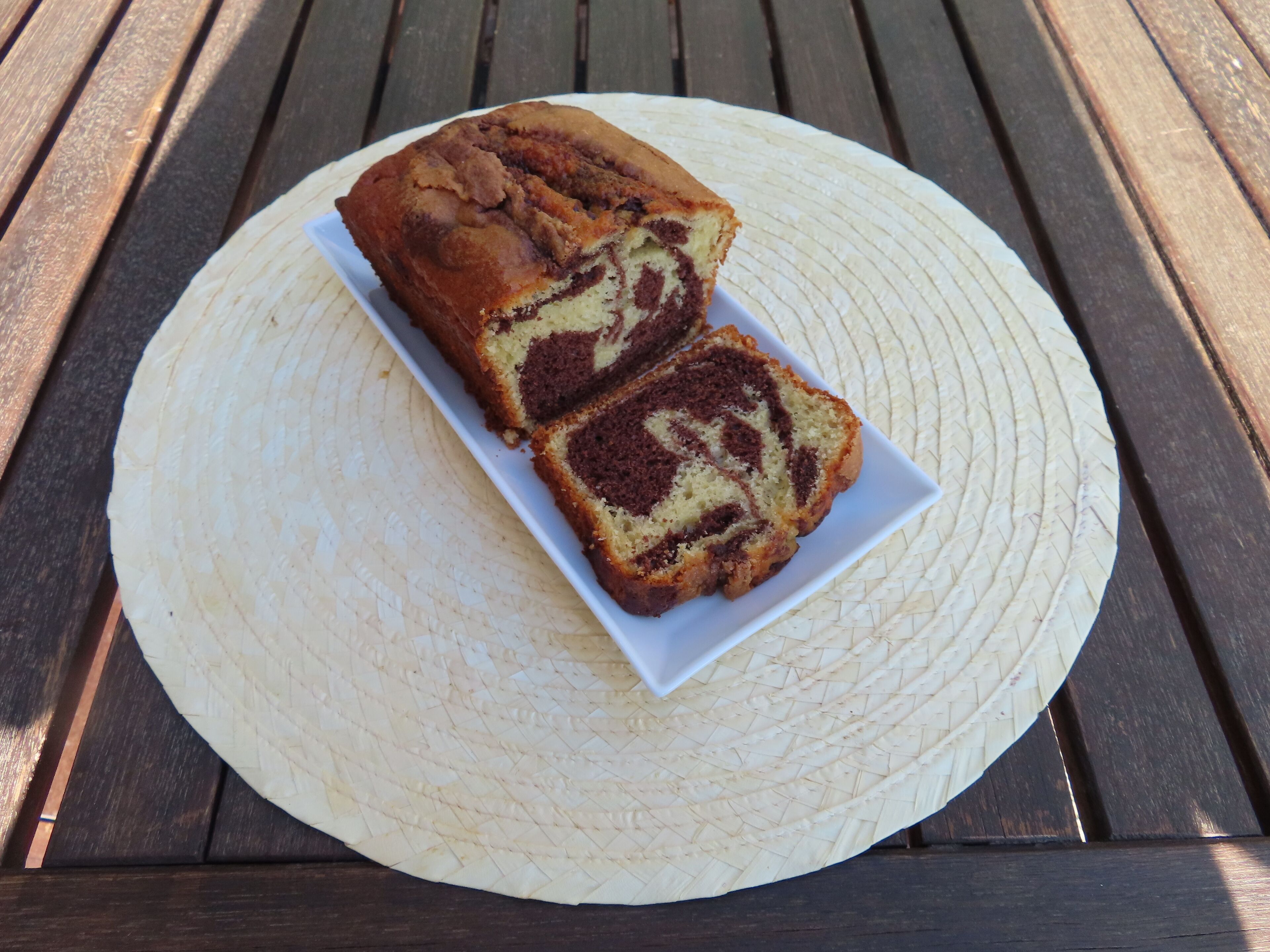 Un pastel marmolado sobre un plato blanco sobre un tapete tejido.