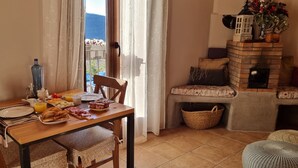 A dining area with a table set for breakfast, a brick fireplace, and a view of the outdoors. - Lo Cel De Tolo (Gavet de la Conca)