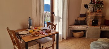 Un comedor con una mesa preparada para el desayuno, una chimenea de ladrillo y vistas al exterior.