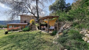 A rustic stone building with a wooden deck and outdoor seating area. - Lo Cel De Tolo (Gavet de la Conca)