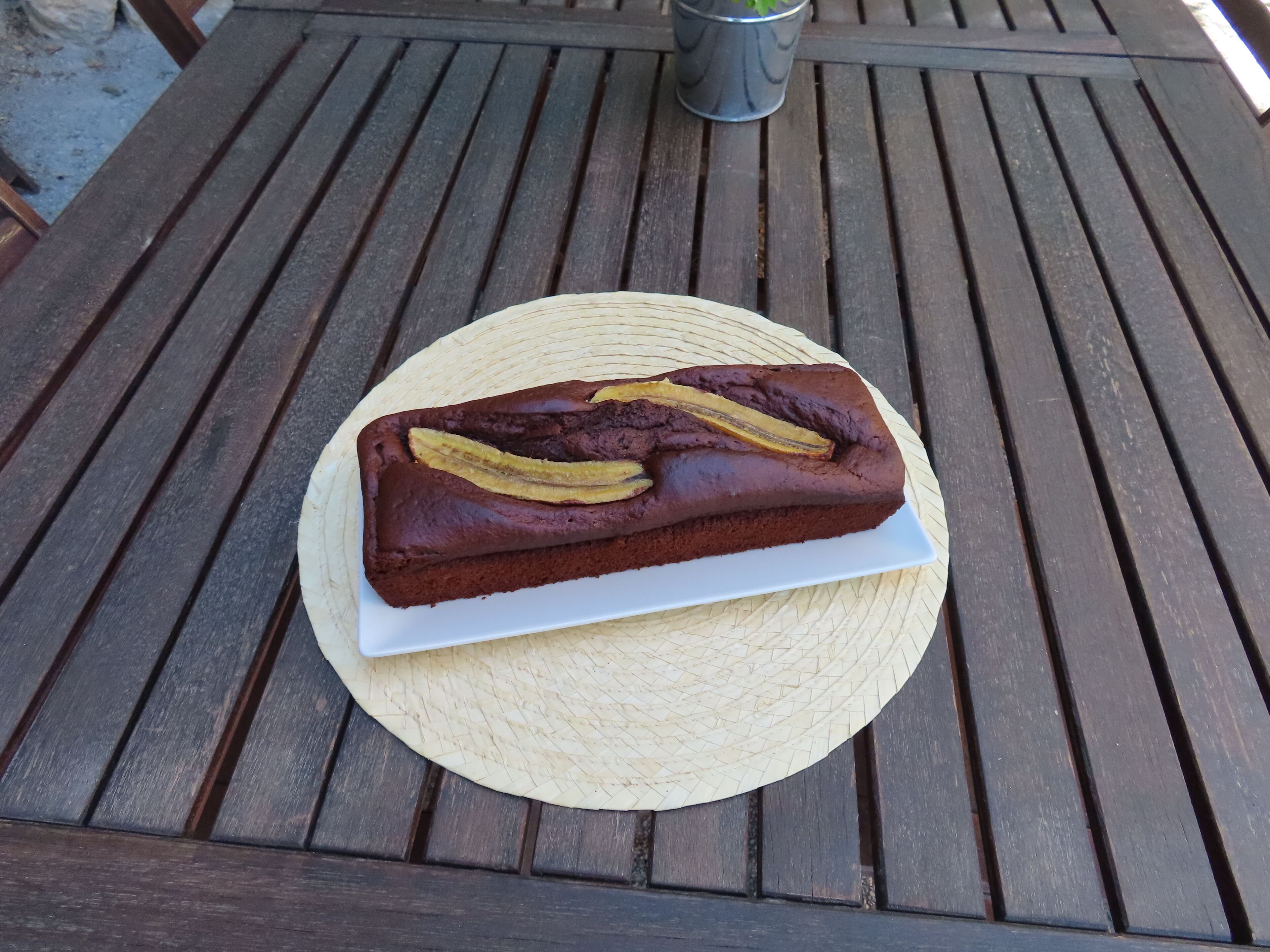 Una barra de pan de plátano sobre un plato blanco sobre una mesa de madera.